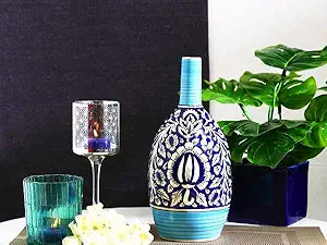 A blue oval-shaped ceramic vase with a floral pattern, displayed alongside a clear glass candle holder and a green plant pot.
