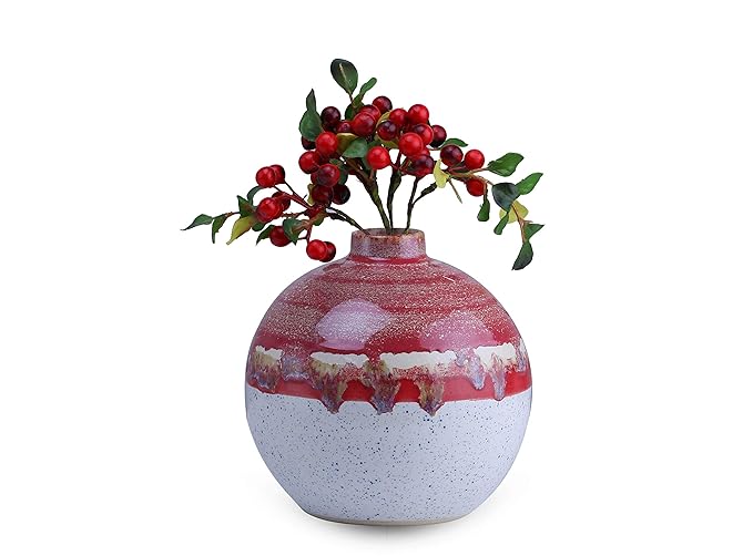 A handmade ceramic vase with a white and red matte finish, featuring a floral arrangement of red berries on top.