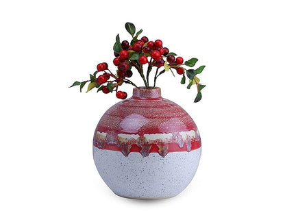 A handmade ceramic vase with a white and red matte finish, featuring a floral arrangement of red berries on top.