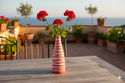 Striped vase with red flowers on a wooden table outdoors