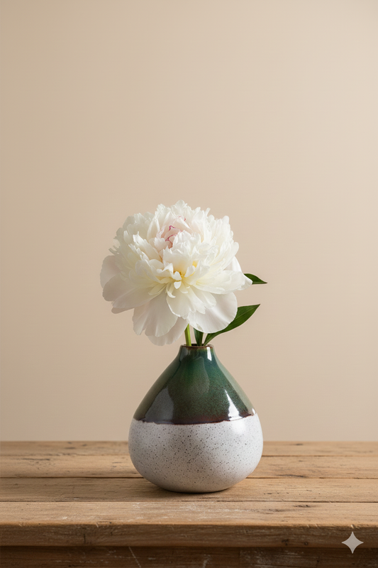 Vase with a white flower on a wooden surface against a beige wall