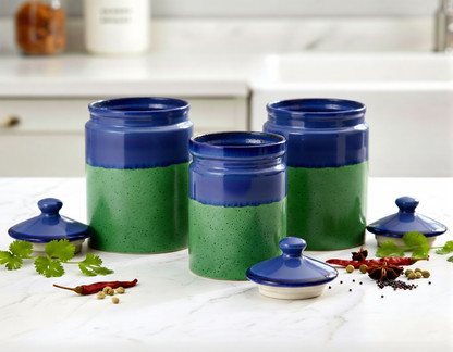 Set of green and blue ceramic canisters on a kitchen counter with spices.