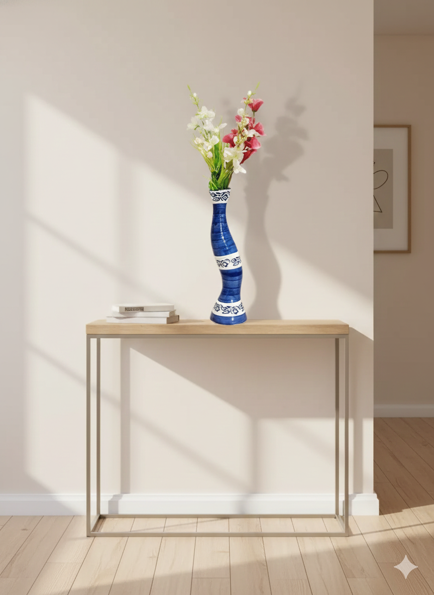 Blue and white vase with flowers on a wooden table against a white wall.