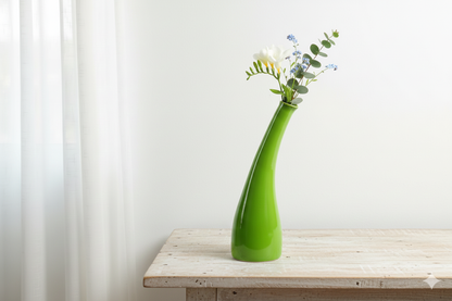 Green vase with flowers on a wooden table against a white curtain background