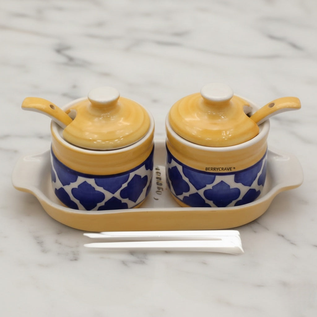 Two ceramic jars with blue patterns and yellow lids on a marble surface.