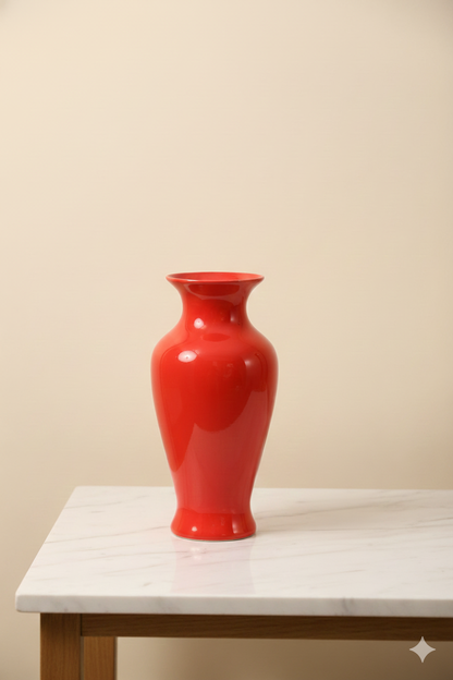 Red vase on a white table against a beige wall