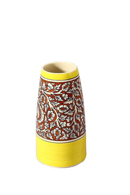 A handmade ceramic vase with a yellow base and a floral pattern in multiple colors on a white background.