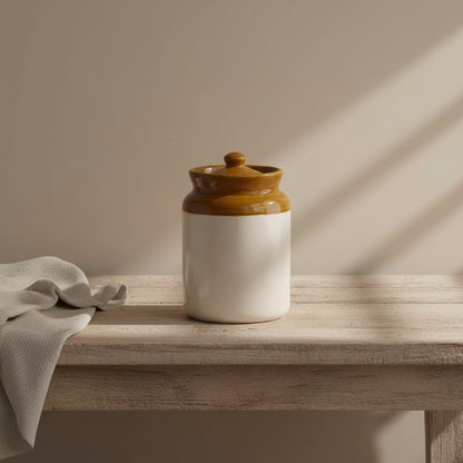 Ceramic jar with a brown lid on a wooden surface with a neutral background