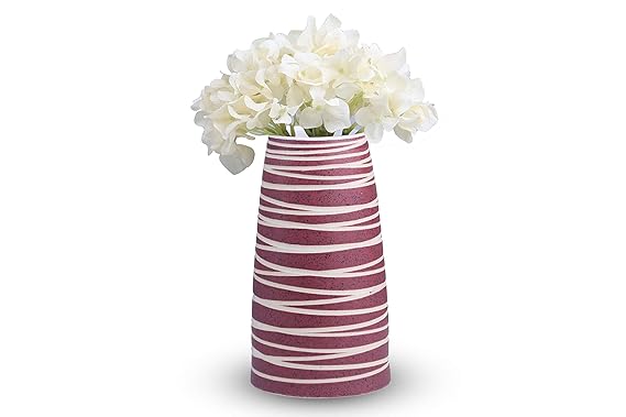 A handmade pink ceramic vase with strip patterns, featuring a glossy finish and containing white flowers.