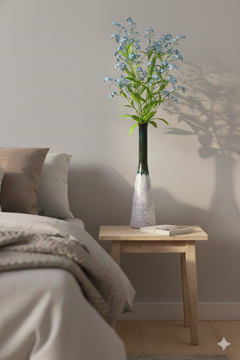 Vase with flowers on a wooden side table next to a bed