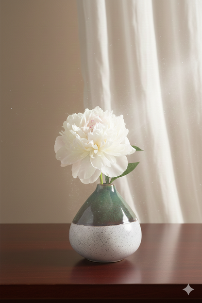 White flower in a small vase on a wooden surface with a neutral background